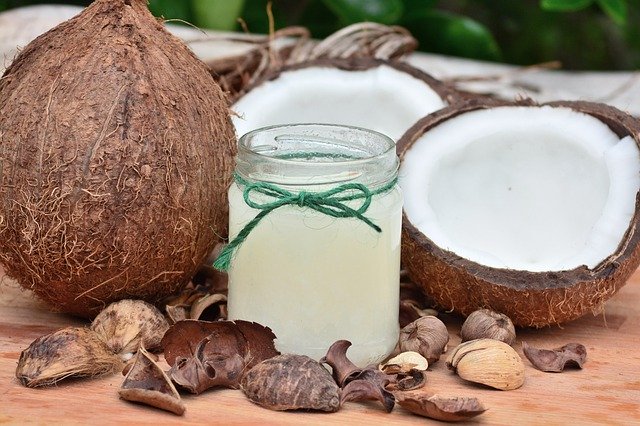 kokosový olej s kokosy v pozadí